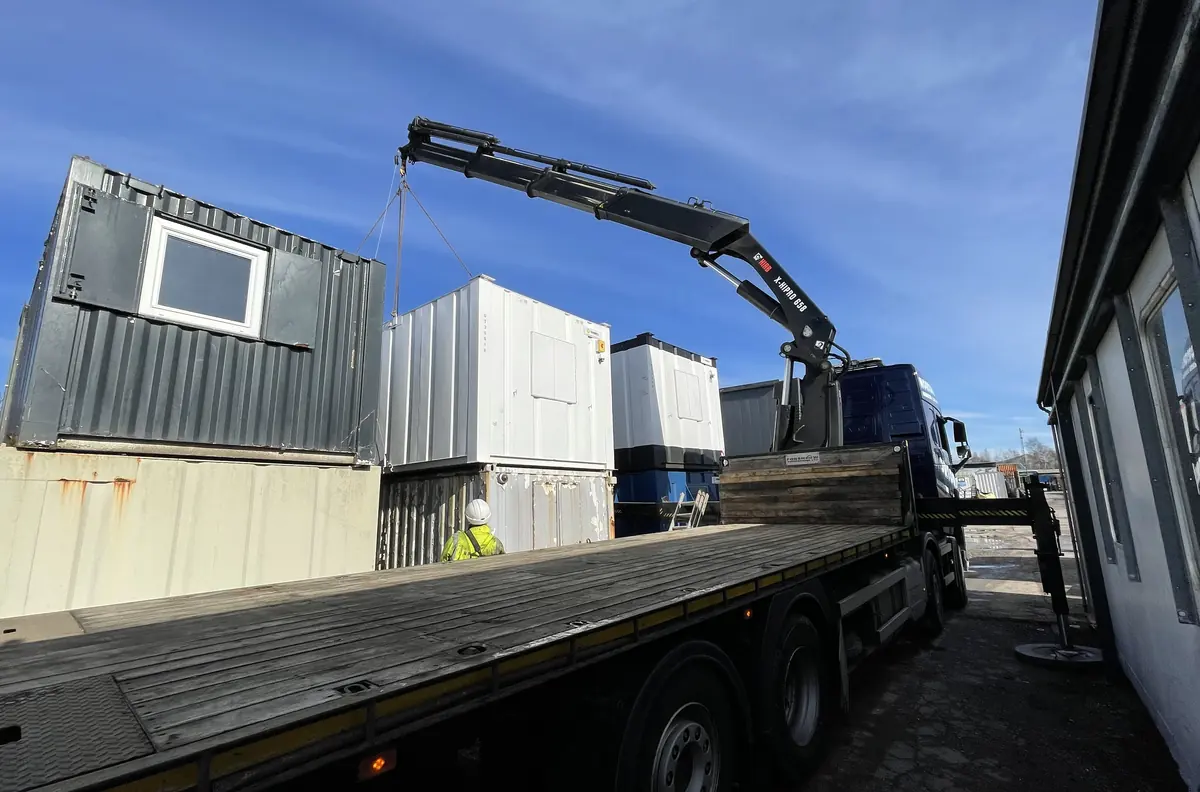 Hiab lorry lifting a used shipping container from a hard standing yard