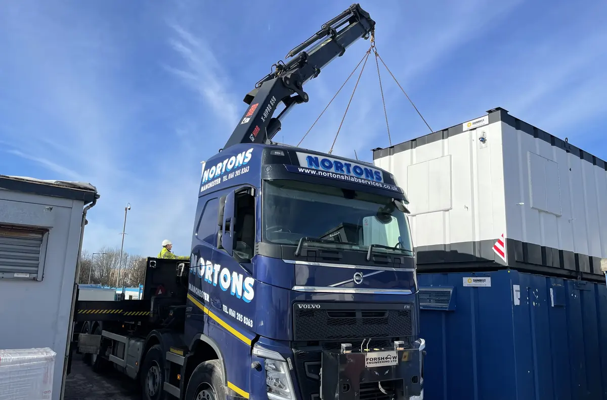 Used site cabin being lifted from a yard onto a Hiab lorry
